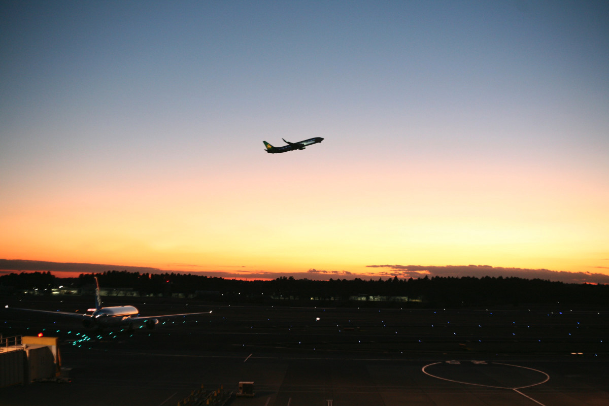 Paysage aéroportuaire de nuit ou à l’aube avec silhouette d’un avion au loin